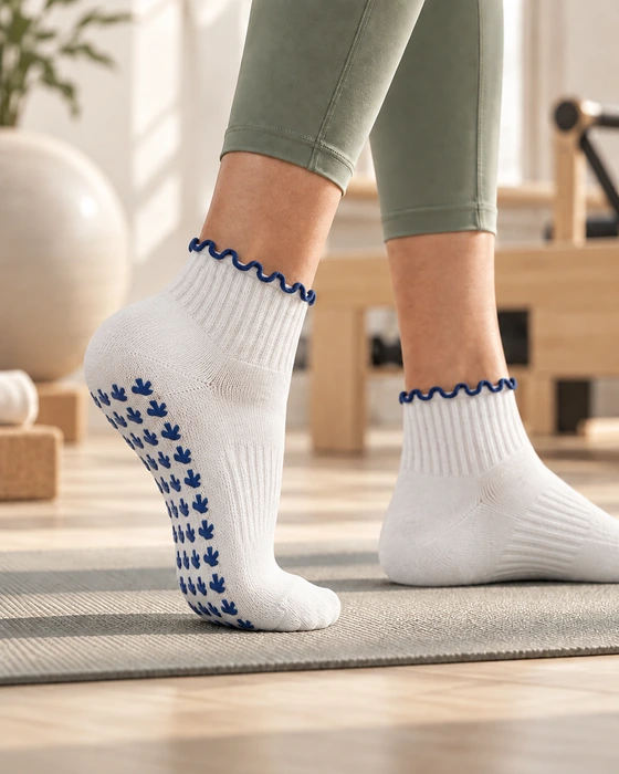 Studio member wearing white scalloped-cuff grip socks during a Pilates or barre session